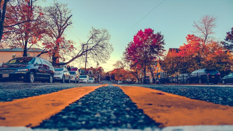 Vibrant autumn street view in Hackensack, NJ with cars and fall foliage.