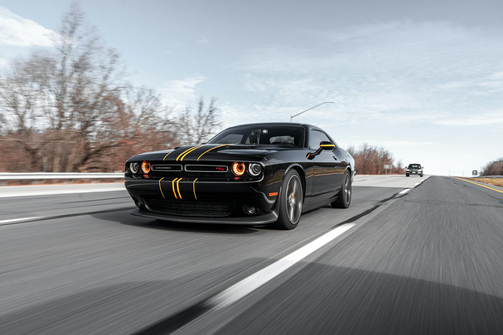 High-performance black car driving fast on a highway with dynamic motion blur.