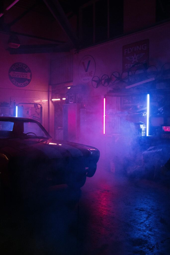 Atmospheric garage scene with neon lights illuminating a vintage car environment, creating an industrial vibe.